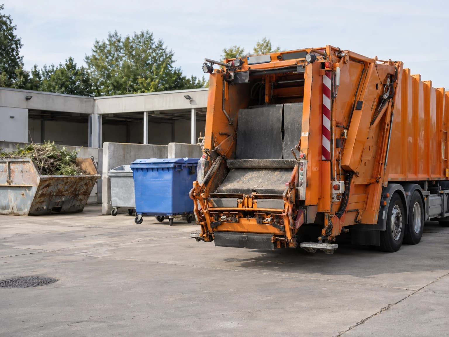 Abfallsammelfahrzeug und geordnete Sammelcontainer auf einem kommunalen Recyclinghof