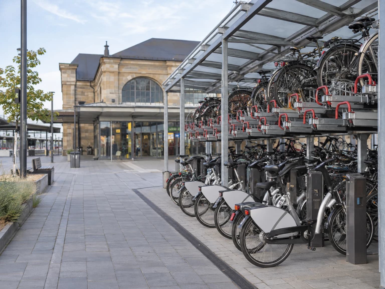 Überdachte Fahrradabstellanlage und Leihräder an einem Bahnhof