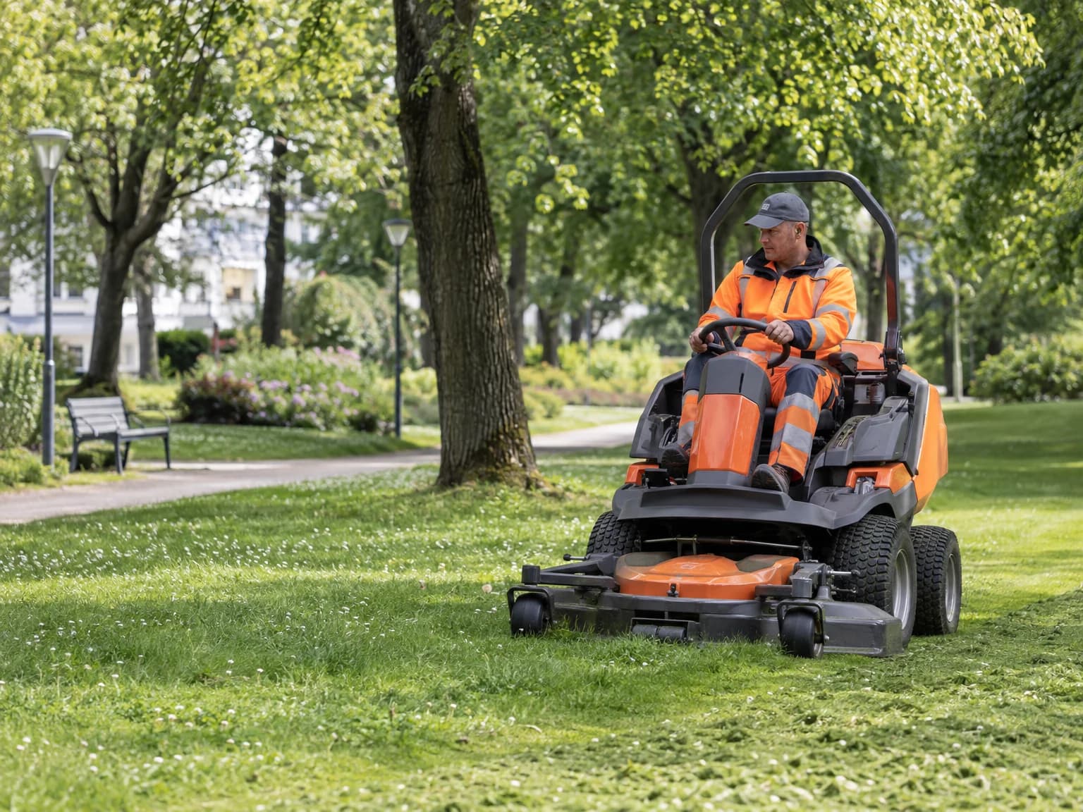 Mitarbeiter des Grünflächenamts mäht mit einem Aufsitzmäher eine Parkwiese