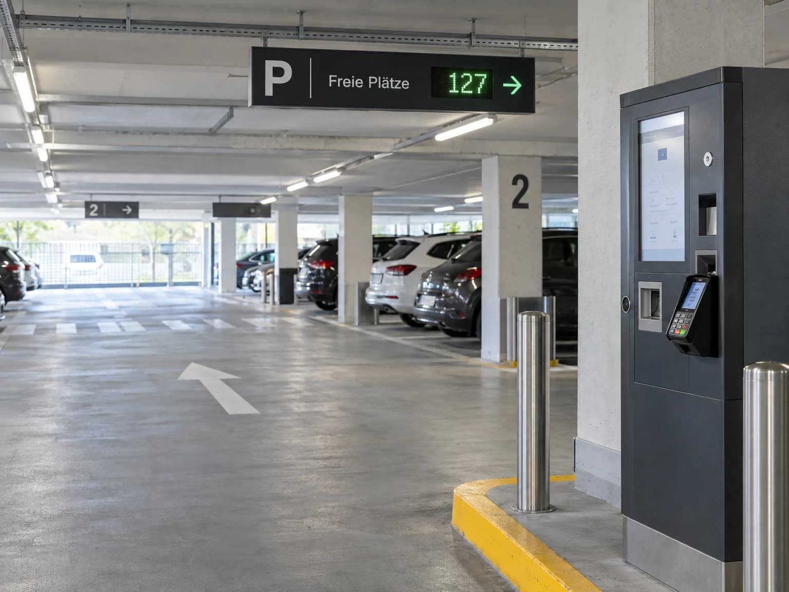Kassenautomat in einem Parkhaus und ein Parkleitschild mit freien Plätzen