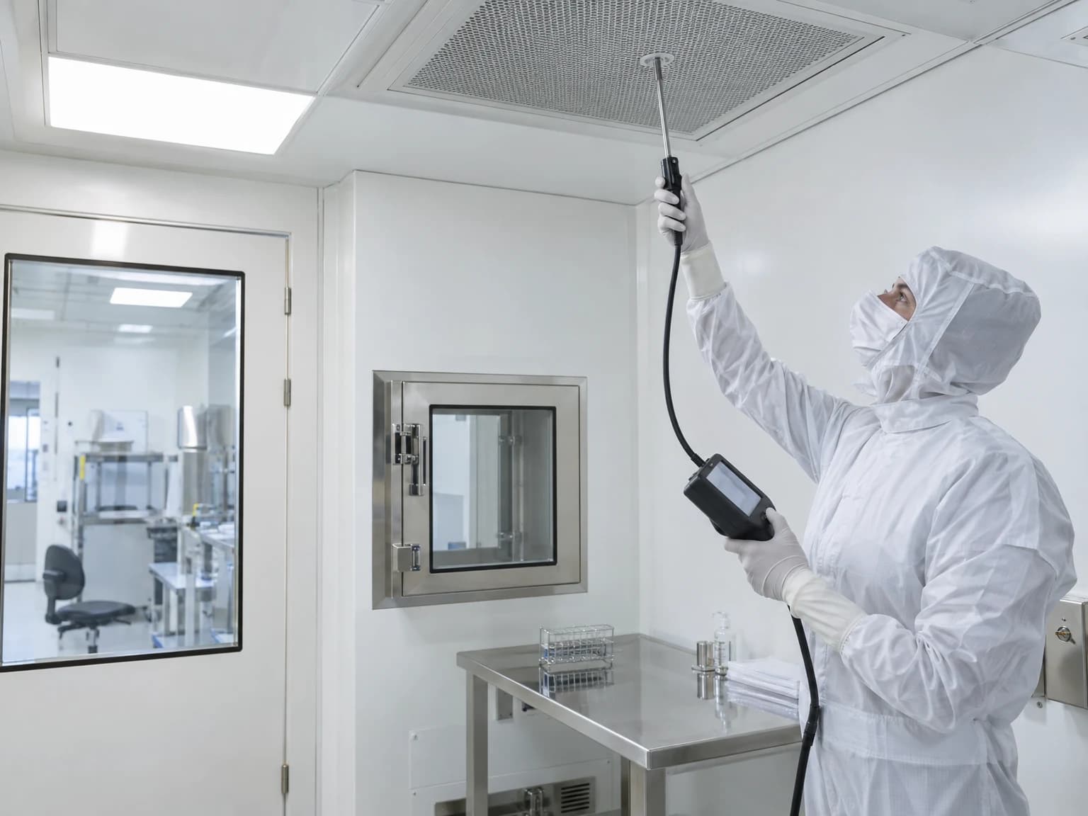 Techniker in Reinraumkleidung misst Partikel in einem Reinraum